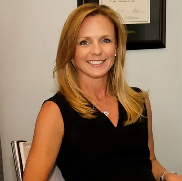 A woman sitting in front of a wall with a smile.